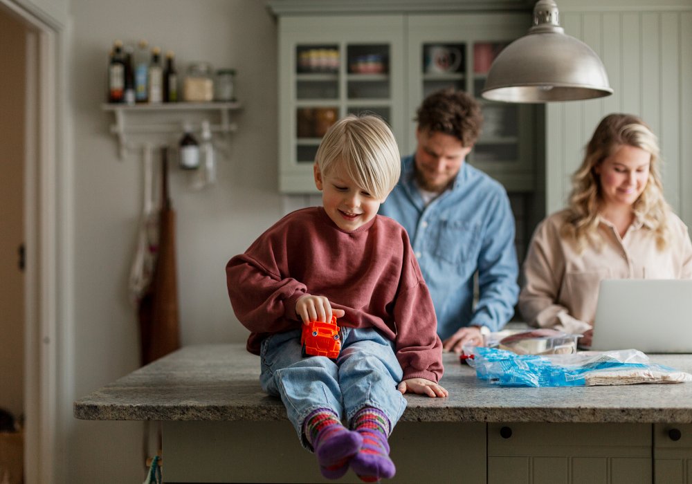 Illustrasjonsfoto: familien samlet ved arbeidsbenken på kjøkkenet.