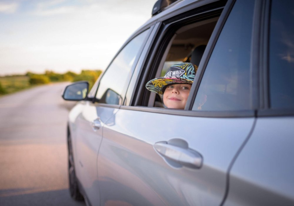 Illustrasjonsfoto: Et barn med caps ser ut av et åpent bilvindu.