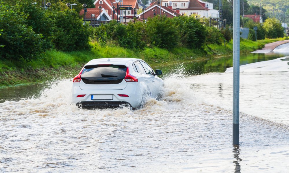 Illustrasjonsfoto: En bil kjører på en vei med flomvann.